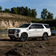 A photo of a white GMC Yukon SUV parked near a lake.